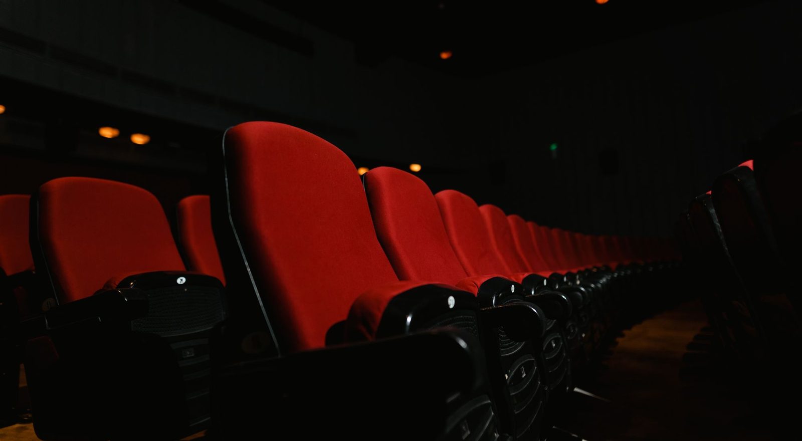Rows of empty cinema seats facing a glowing screen